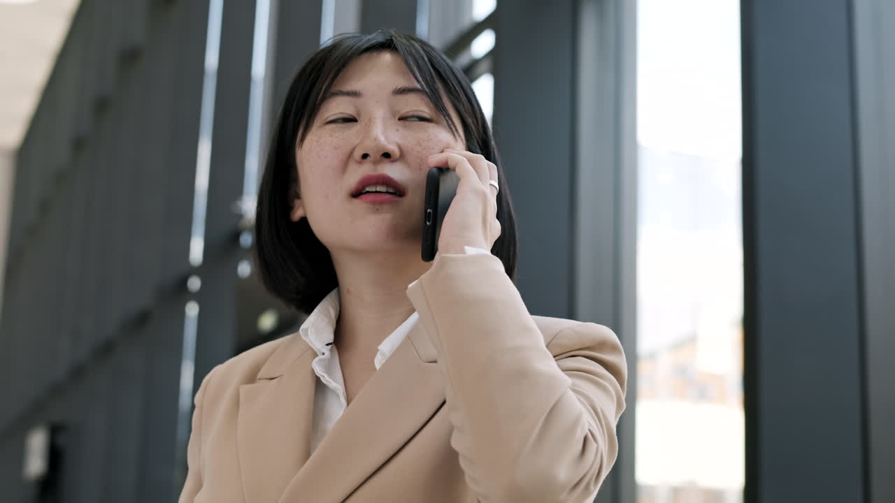 젊은 아시아 사업가 여성이 전화로 이야기하고 있습니다.