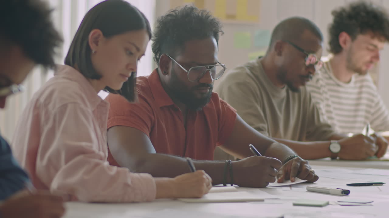 Diverse Migrant Students Writing at Desk during Exam