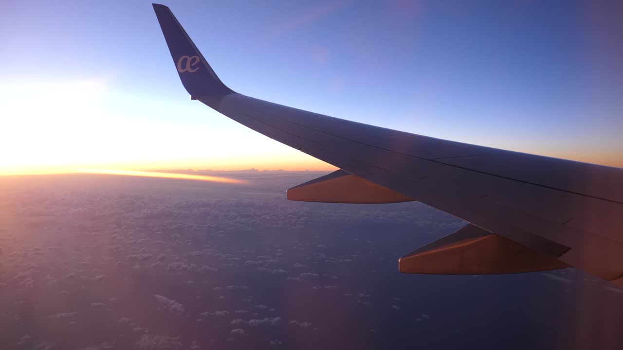 Airplane Wing Flying Above Clouds During Golden Hour Sunset