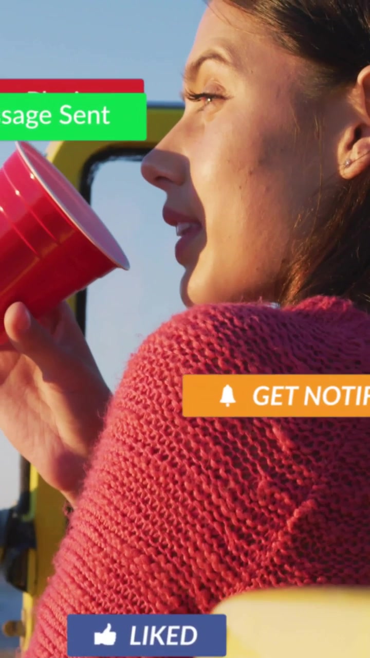 Video verticale: Donna in auto che sorseggia da una tazza rossa, specchio che genera avvisi social intorno al viso, coinvolgente.