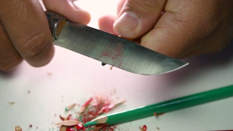 Footage-of-hands-slowly-sharpening-a-pencil-and-some-coloured-pencils-with-a-sharp-knife