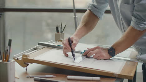 close up of architect hands making house blueprint in the office near window. concept: architecture blueprint house paper work