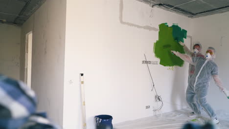 una pareja de trajes con máscaras corre hacia una pared pintada en una habitación vacía.