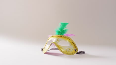 video of masquerade mask with green and pink feathers on white background with copy space