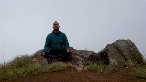 man meditating at mountain rock with white mist background from flat angle