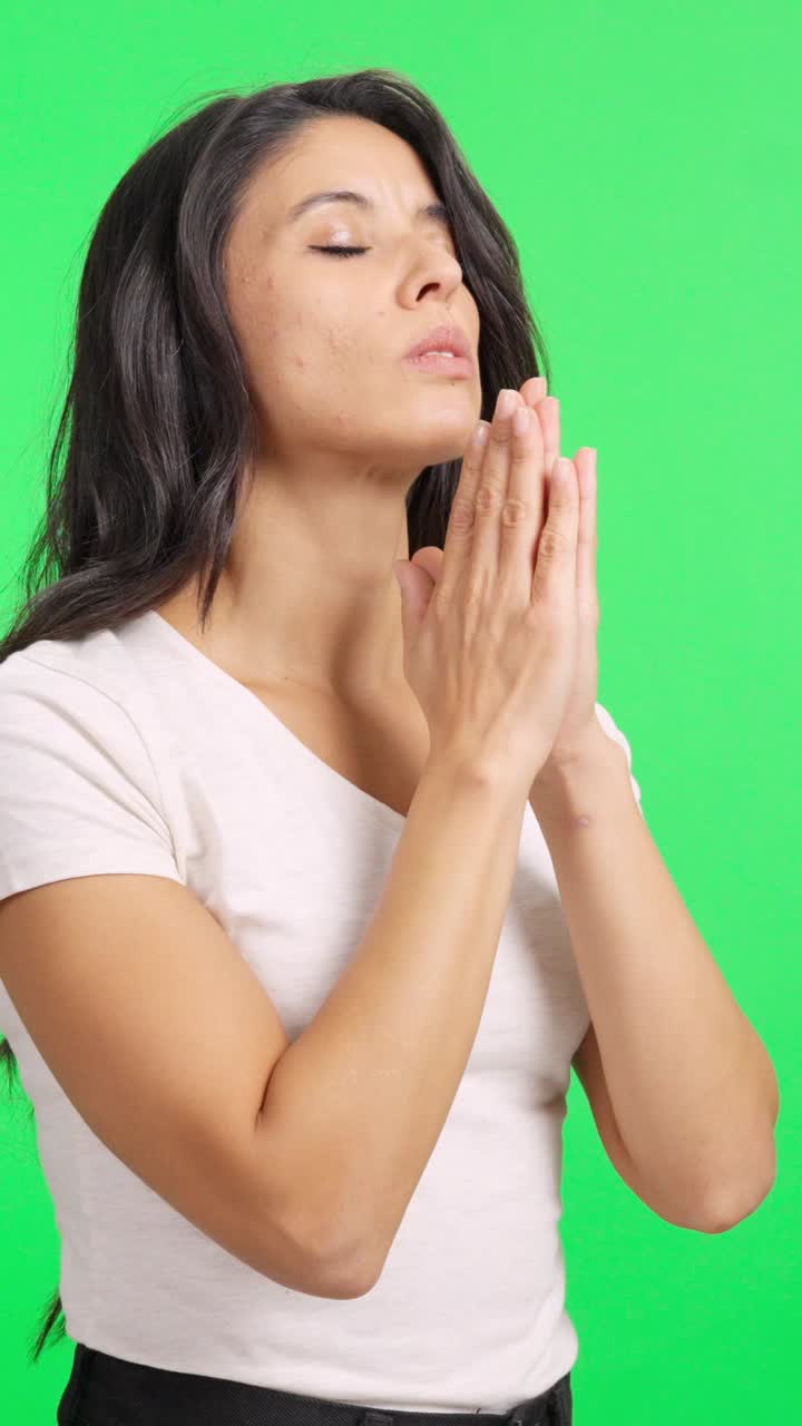Donna con le mani giunte che prega su schermo verde