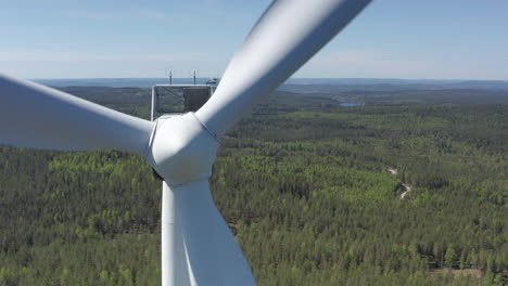 close-up aerial view of rotating wind turbine in forested landscape