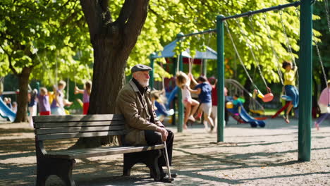 elderly man relaxing in park with children playing