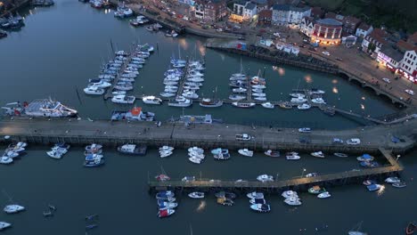 Parallax-drone-shot-of-Scarborough-harbor-with-boats-parked-near-a-busy-road-during-evening-in-England