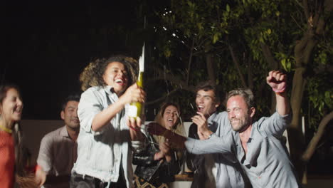 happy curly-haired woman popping champagne at outdoor  party