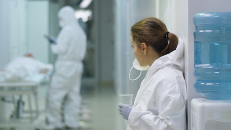 Tired-Female-Doctor-in-Protective-Suit-Drinking-Water