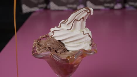 pouring caramel over ice cream dessert with chocolate side view