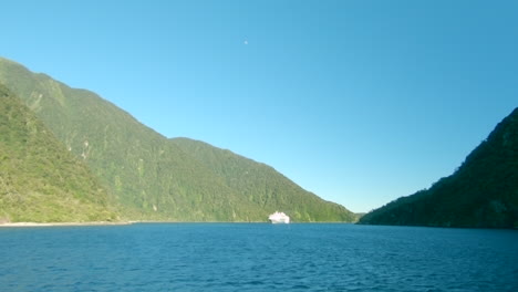 wide shot of a cruise ship entering a fiord, milford sound, new zealand