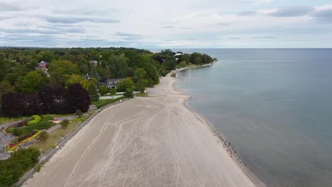 uncrowded, deserted beach with lifeguard tower hut along treed shoreline and clear blue water