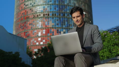 Businessman-receiving-good-news-on-laptop-at-street.-Freelancer-working-computer