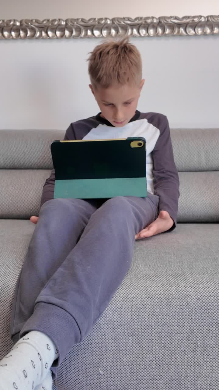 Boy using a tablet on a couch