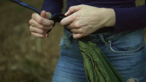 footage of a women clipping in a carabiner so she can fix a hammok between to trees in the forest in germany