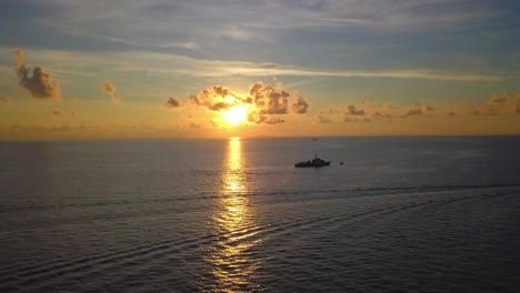 vuelo aéreo con espectacular puesta de sol sobre el océano y un gran barco en mabul, malasia