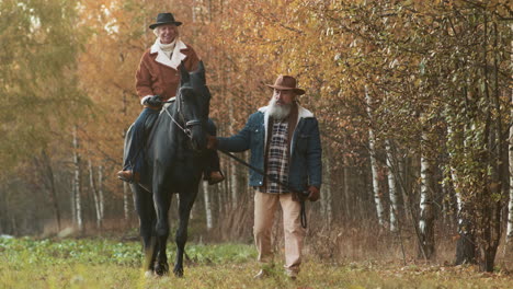 vrouw zit op een paard bij het bos.