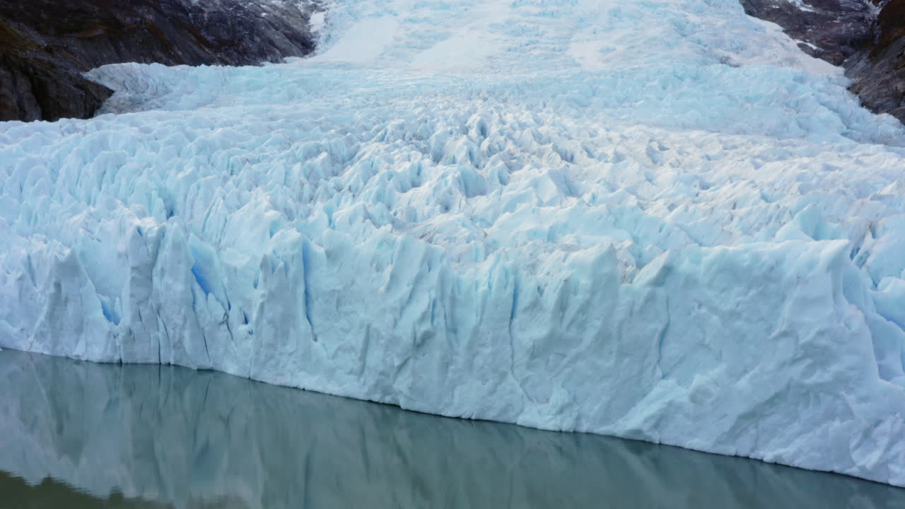Huge glacier face rising from sea with vivid blue ice layers and cold Patagonian water below, Pia glacier, Beagle Channel Cape Horn Argentina, natural backdrop background