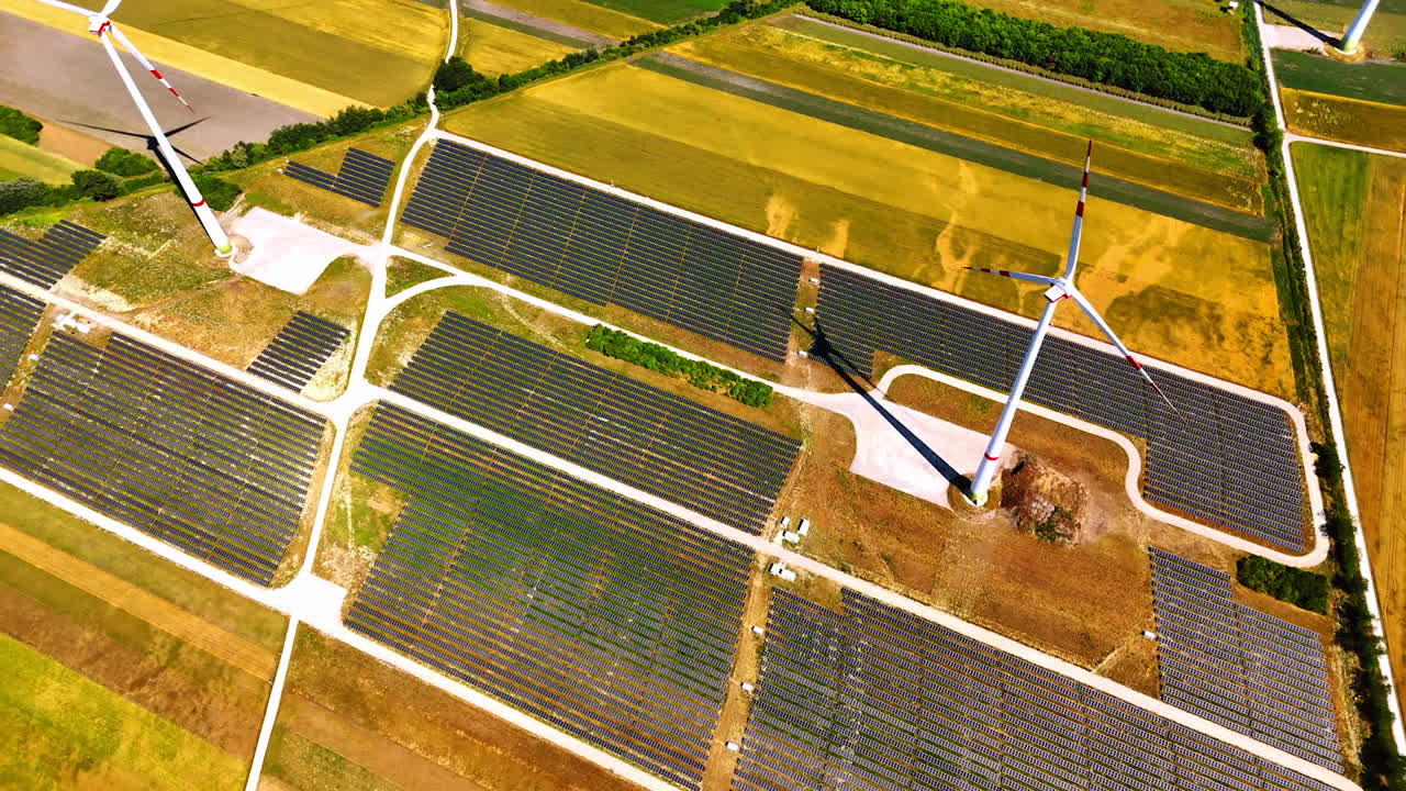 Flight over the site covered with solar panels. High wind turbines rotate in the wind. Green power concept