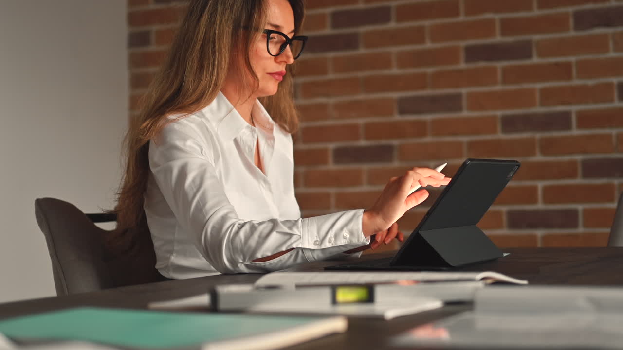 Woman working on a tablet with a stylus pen at an office