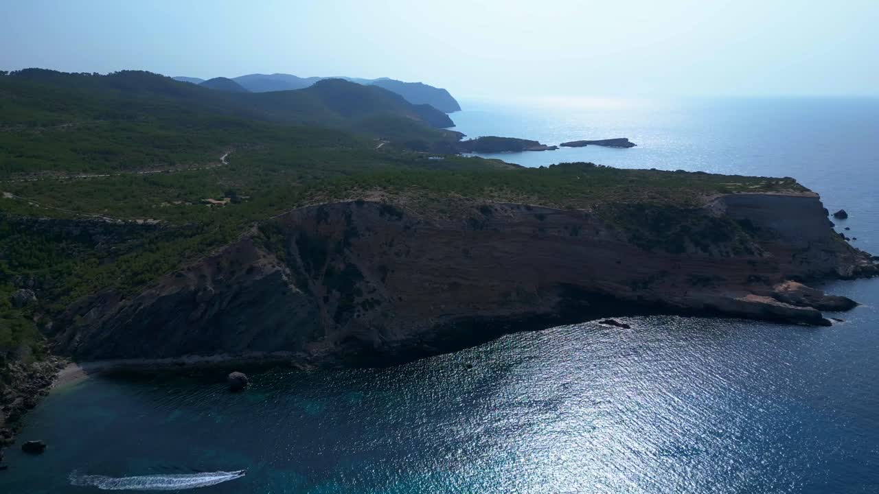 Ibiza, Spain, overlooking a picturesque bay with turquoise water and boats sailing on a sunny summer day. Best aerial view flight