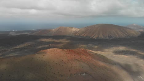 Tire-Hacia-Atrás-Del-Disparo-Del-Dron-Que-Desciende-Detrás-De-Un-Volcán-Rojo-En-Un-Día-Nublado