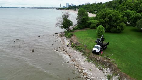 city construction workers assessing rising water levels and using flood prevention methods to protect a lakefront park in milwaukee, wisconsin.