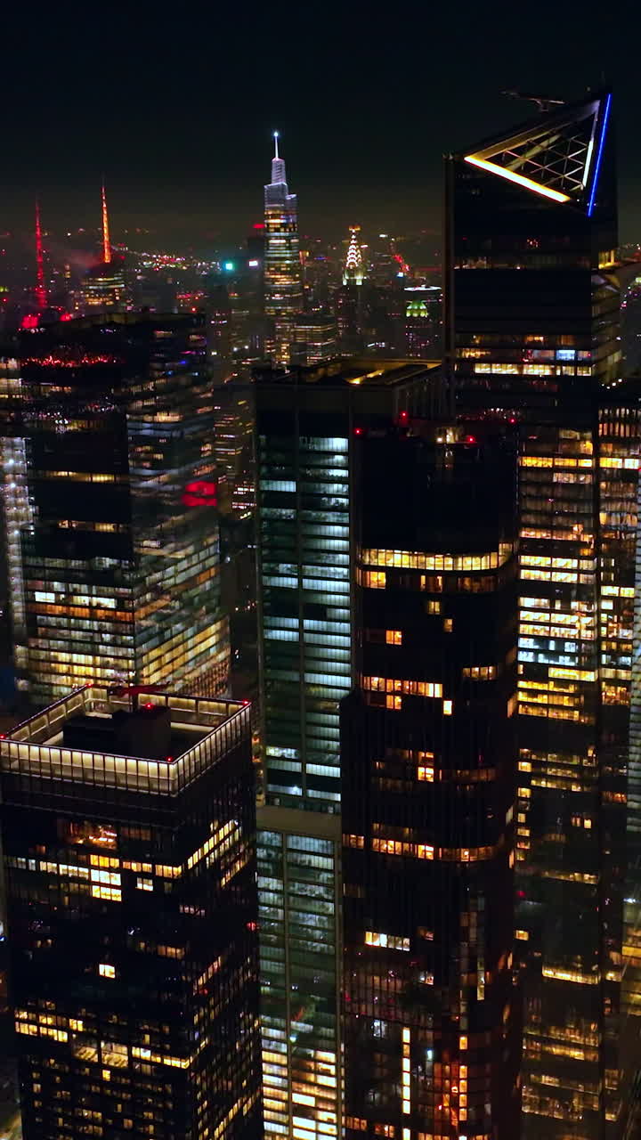 Colorful diverse lights of nighttime New York. Crazy traffic flow around the streets of metropolis at night. View from above. Vertical video