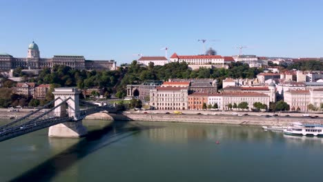 drone pan reveals széchenyi chain bridge spanning danube river and buda castle