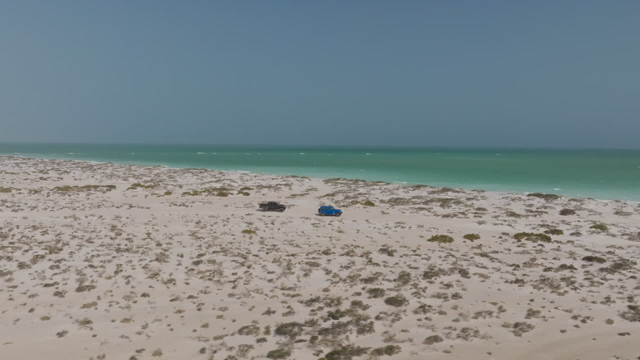 Two cars driving along a remote beach in Bar Al Hikman, Oman, peaceful and free