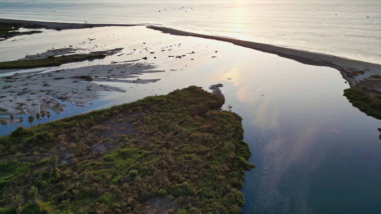 Aerial drone view of wetlands in Baja California at sunset, with calm waters reflecting the soft sky colors