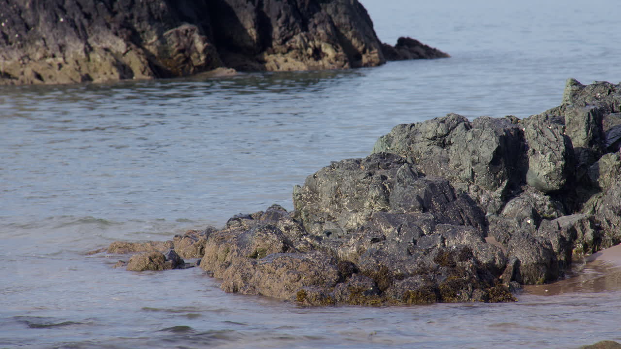 mid Shot of small Waves breaking over rocks at Llanddwyn beach and at the Newborough National Nature Reserve