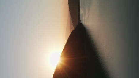 vertical view of beautiful frumoasa dam in harghita county, romania with sun rising behind silhouetted mountain forest at dawn