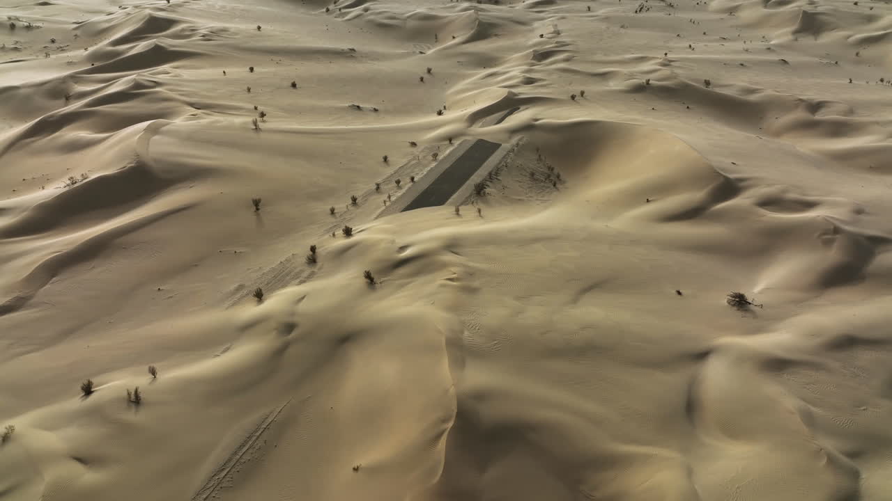 vista aérea volando alrededor de la carretera del desierto parcialmente cubierta de arena, en el soleado dubai, eau