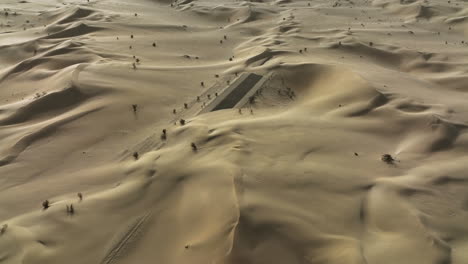 aerial view flying around the partly sand covered desert road, in sunny dubai, uae