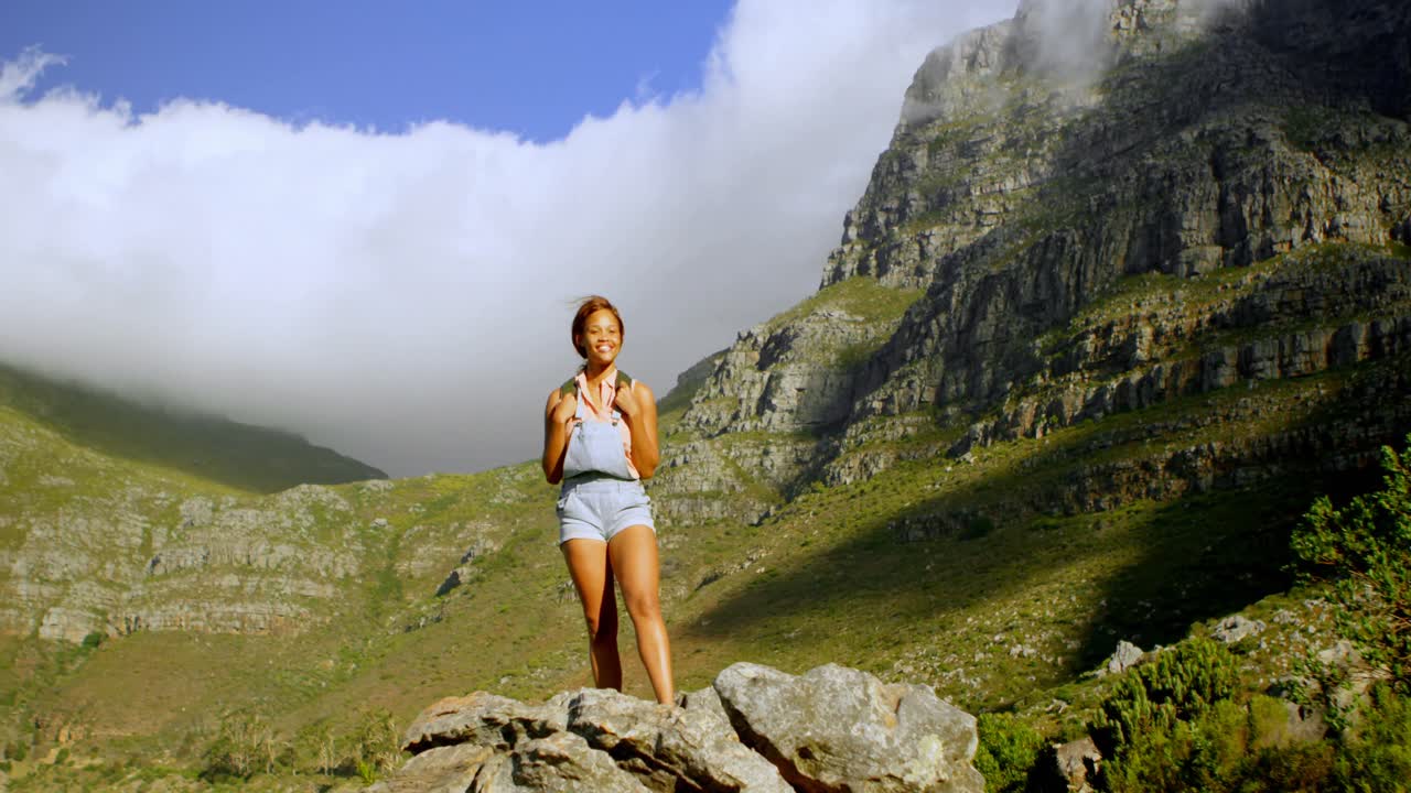 excursionista de sexo femenino de pie en una roca 4k