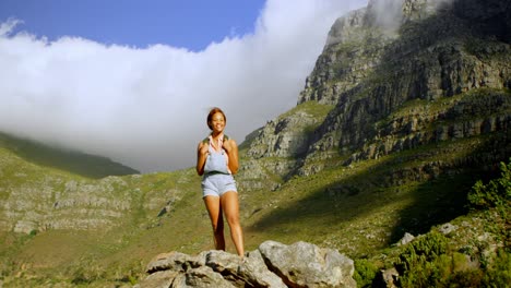 female hiker standing on a rock 4k