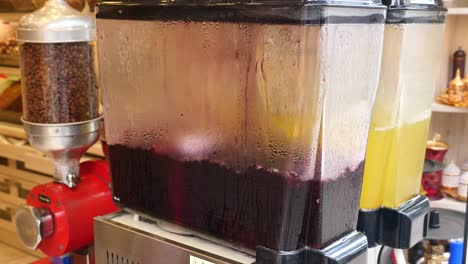 close-up of two drink dispensers with red and yellow beverages