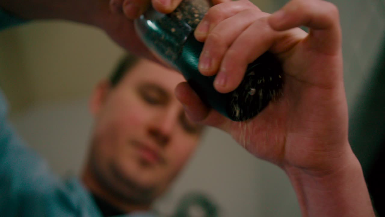 요리를 위해 검은 후추를 갈고 있는 청년