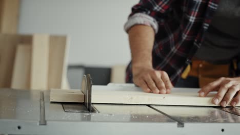 carpenter using table saw to cut piece of wood