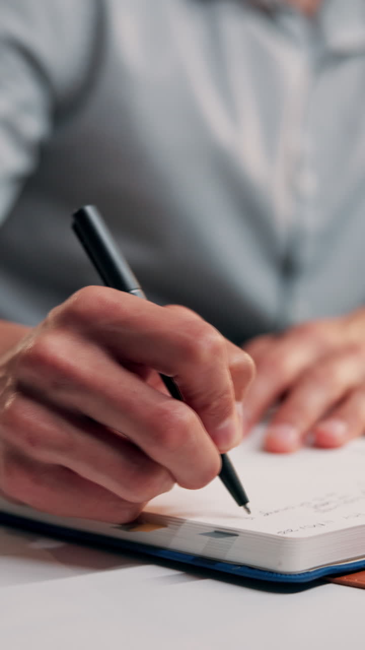 Close-up of a Person's Hand Writing in a Notebook with a Pen