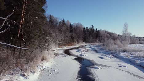 Winter-partially-frozen-river-in-forest-landscape-aerial-view