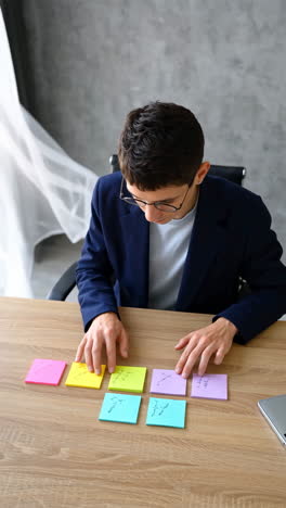 person organizing ideas with colorful sticky notes on a wooden desk