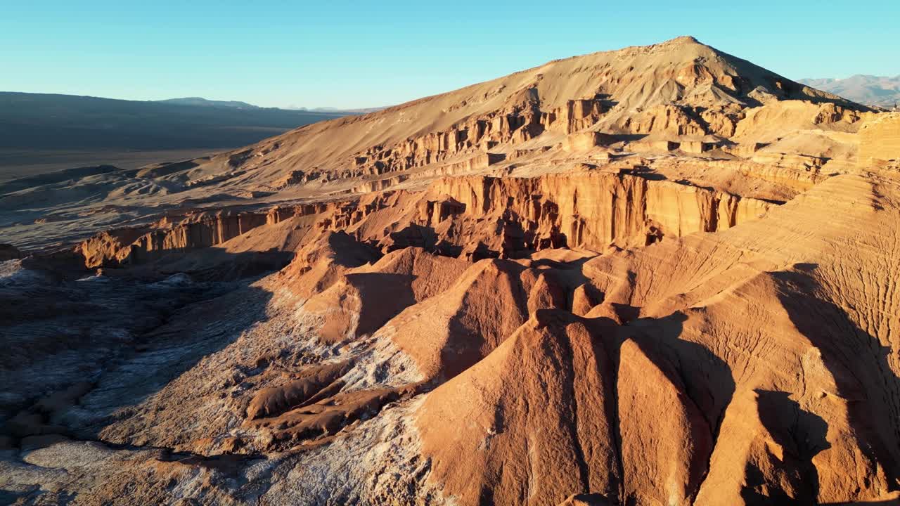 Sweeping 4K drone shot of glowing desert ridges and salt plains surrounding Valle de la Luna at golden hour