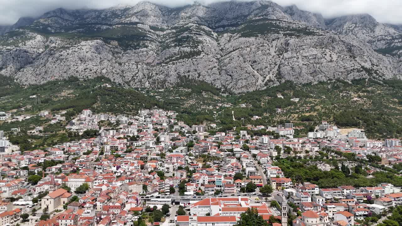 Vista aerea con drone della città portuale di Makarska, Croazia, paese balcanico, con i monti Biokovo