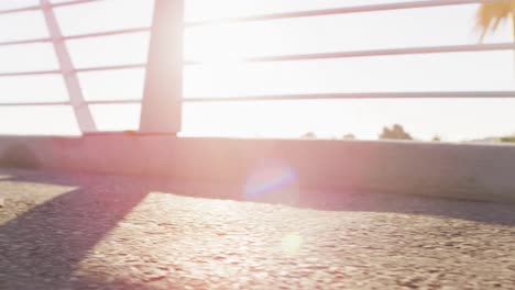 Feet-of-man-exercising-outdoors,-running-on-sunny-footbridge-in-city