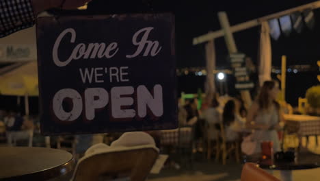 El-Cartel-De-La-Tienda-Cerrada-Se-Gira-Para-Abrir-Por-La-Noche-En-El-Fondo-Del-Café-De-La-Playa-Tesalónica,-Grecia