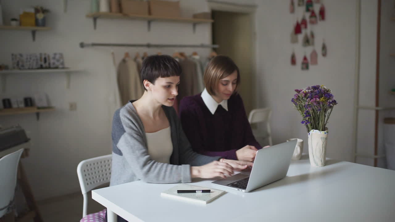 Due giovani donne sedute al tavolo usano il notebook. Una donna lavora al computer portatile.